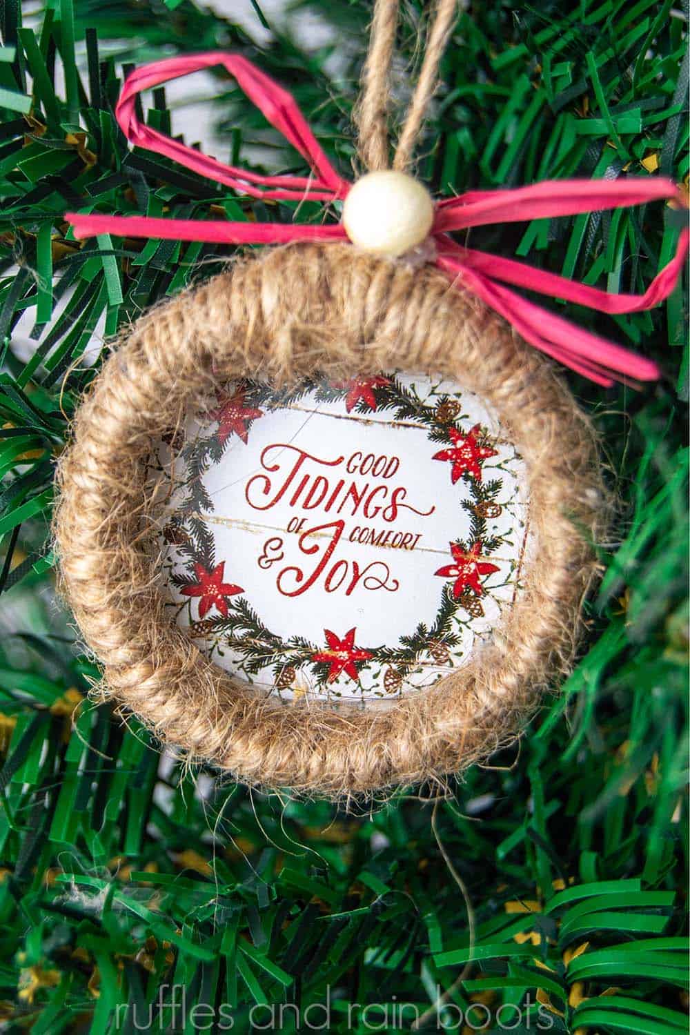vertical close up image of a twine wrapped wreath with red ribbon and Dollar Tree calendar page good tidings of comfort and joy