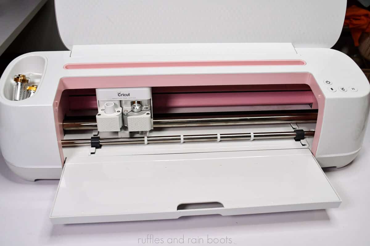 Close up picture of an open Cricut Maker in rose on a craft table for the article which cricut should I buy.