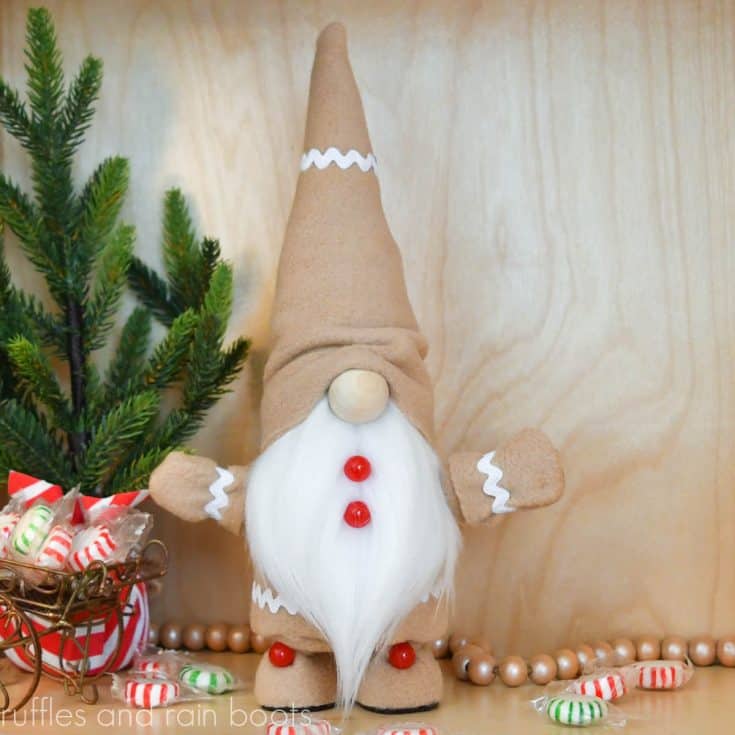 square image of a Christmas gingerbread gnome with arms and legs that pose on a light wood holiday background with peppermint candy