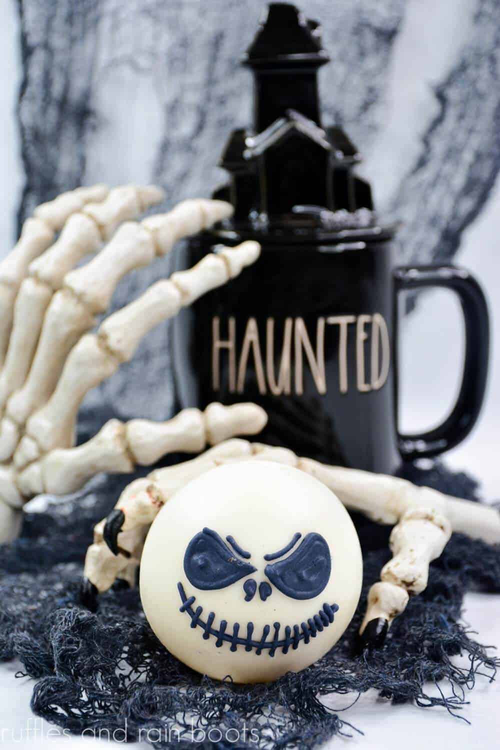 Jack Skellington hot chocolate bomb on Halloween background with Rae Dunn mug, black webbing, and skeleton hands