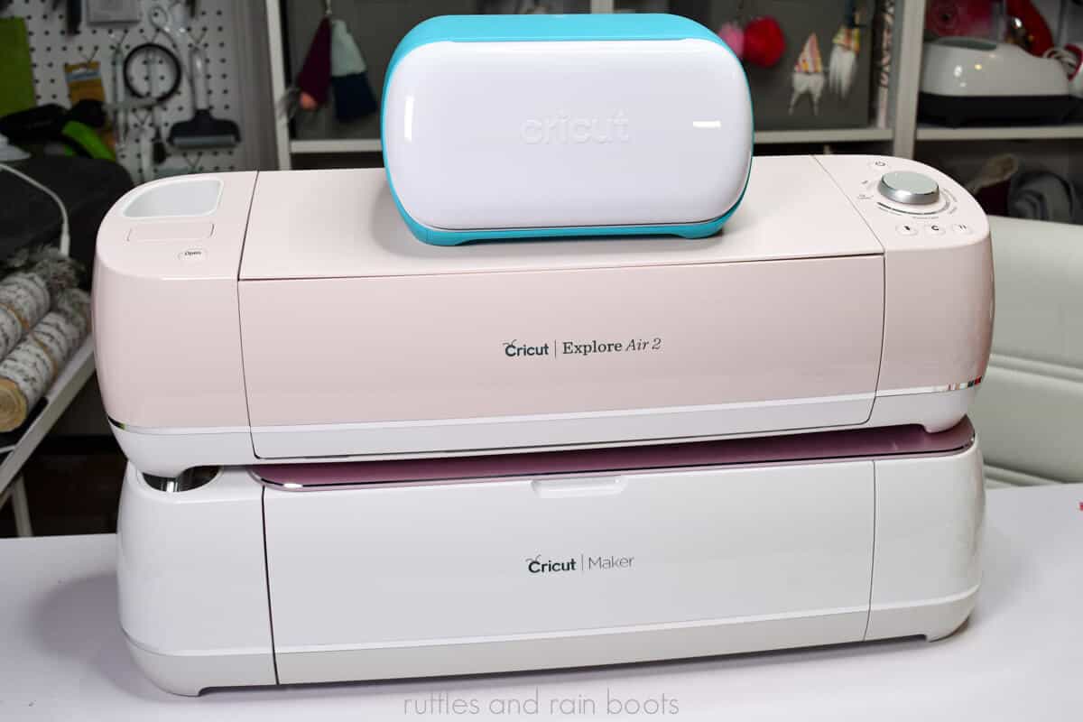 horizontal image of Cricut Joy Cricut Explore Air 2 and Cricut Maker stacked in a craft room to help people decide which Cricut machine to buy