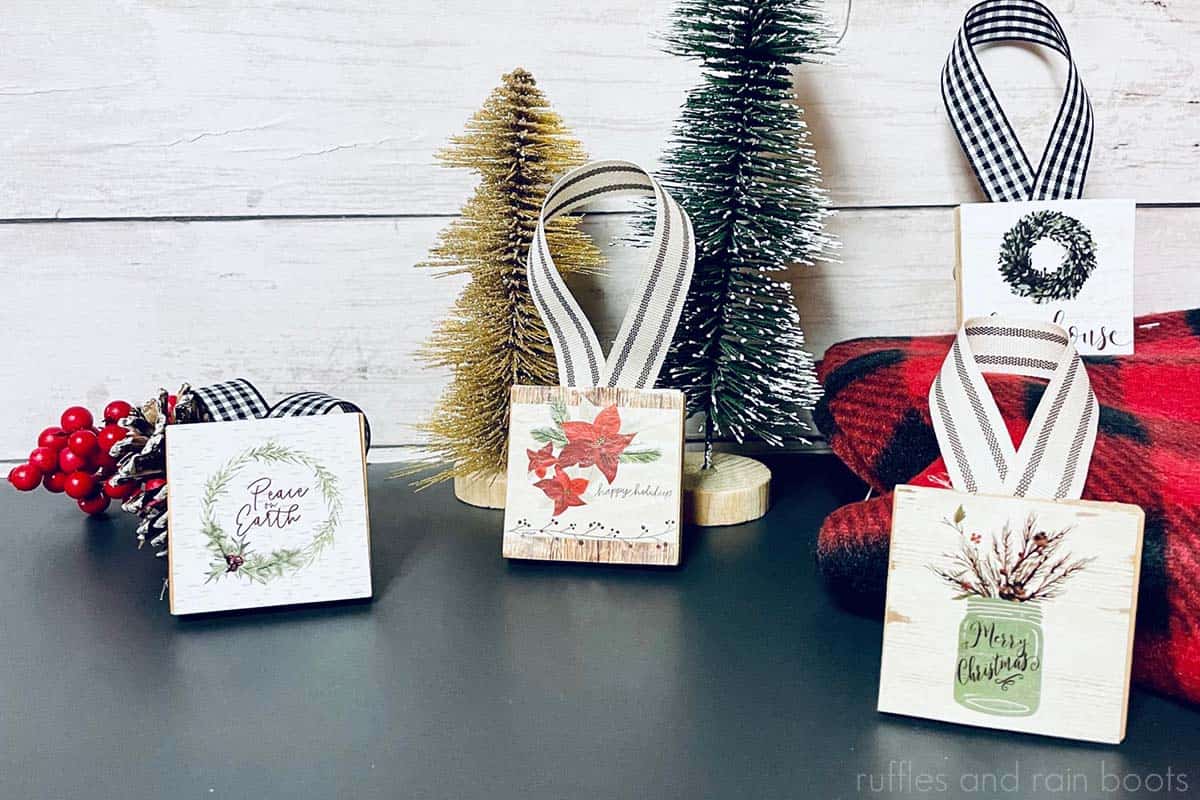 horizontal image with Christmas decor on a wood wall background showing four tumbling tower ornaments made with Dollar Tree calendars and ribbon