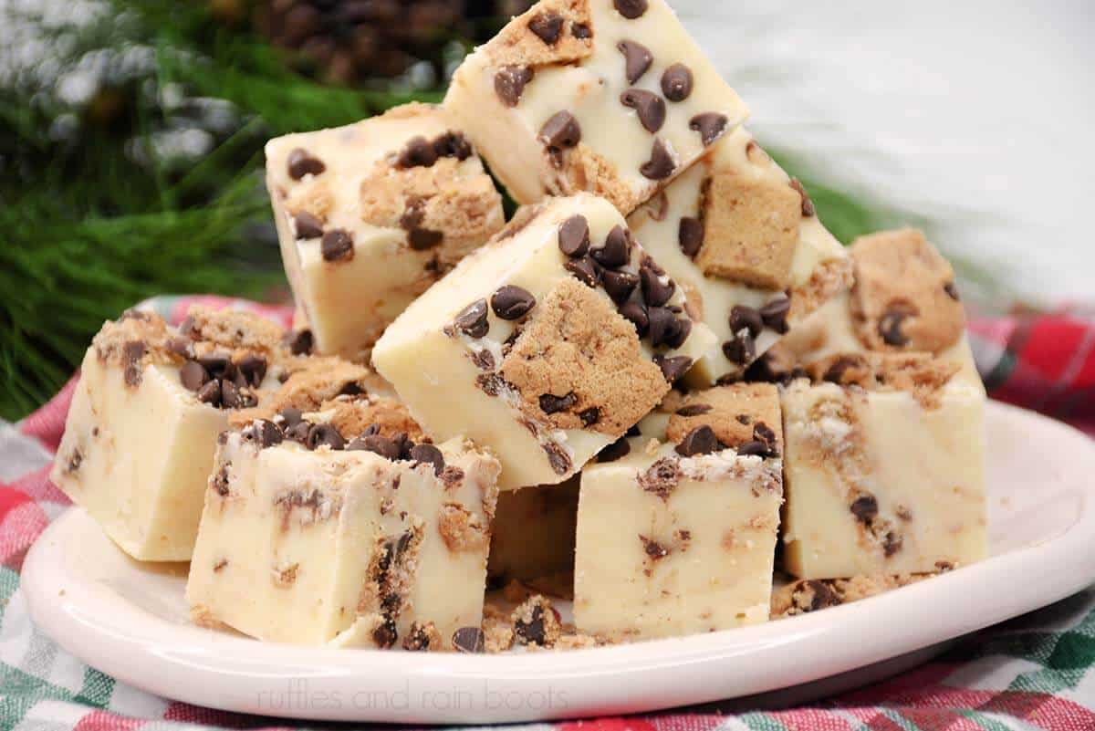 horizontal image of milk and cookies fudge recipe made with mini chocolate chips and pre made Chips Ahoy cookies on a white plate on a plaid napkin in front of greenery