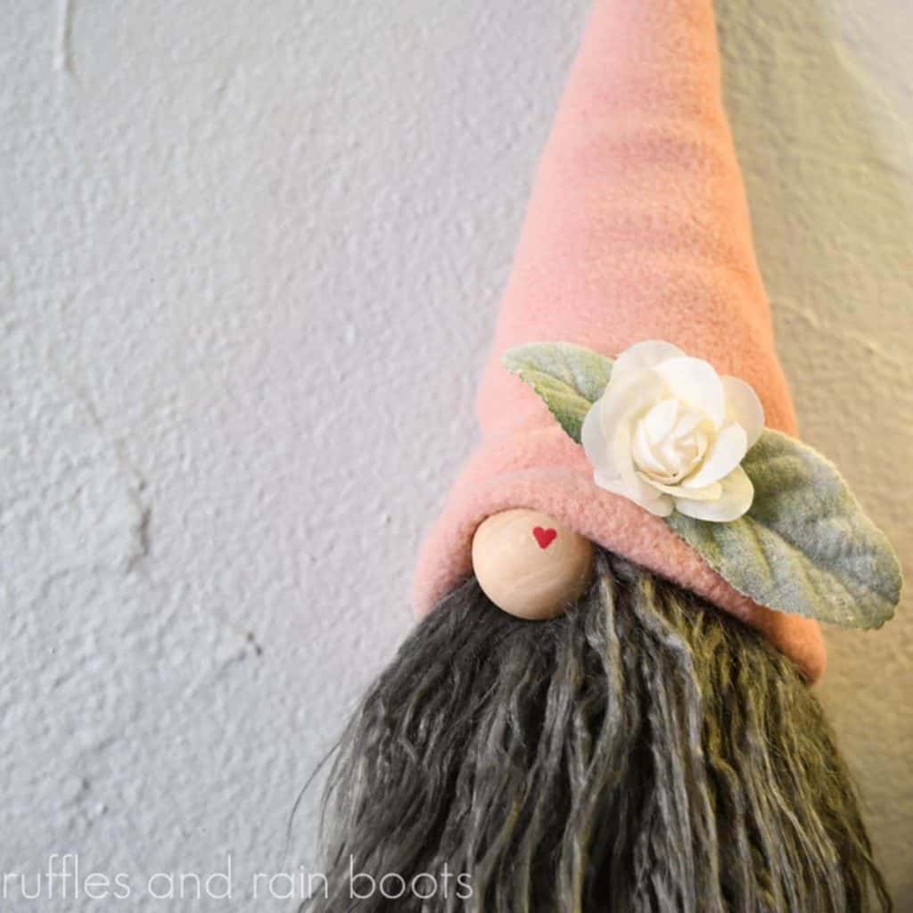 square image of close up of gnome with long legs showing heart detail on gnome nose and flower and leaf detail on no sew gnome hat