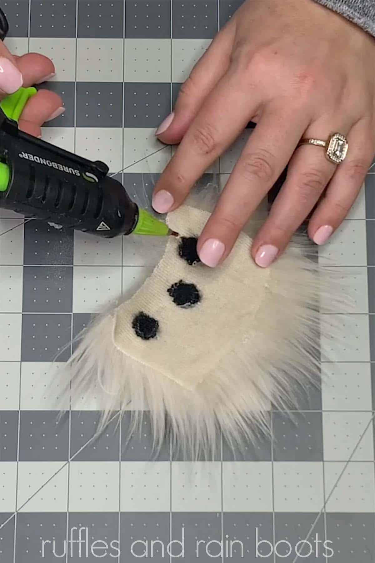 Close up image showing a crafter using a hot glue gun on a grid cutting mat to make custom patterns in faux fur of black spots in blonde gnome beard.