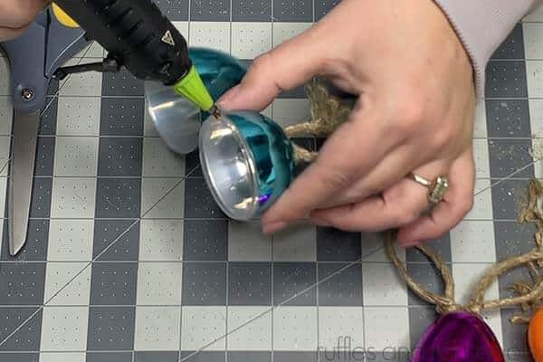 Close up image showing a crafter sealing the plastic eggs together with a bead of hot glue.