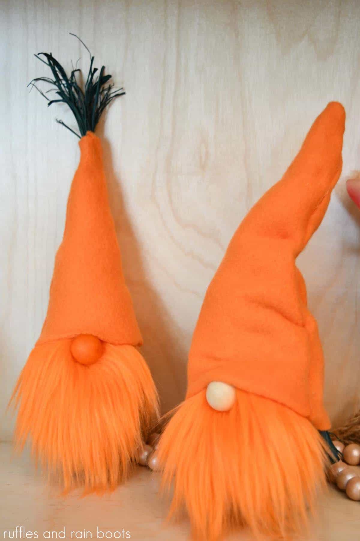 Vertical image showing two carrot gnomes for Easter with orange hats, green raffia, orange gnome beards from fur and a light wood background.