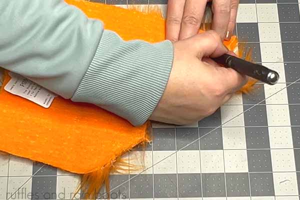 The fourth step in carrot gnome creation is to cut a half wrap gnome beard from orange faux fur with an Exacto knife.