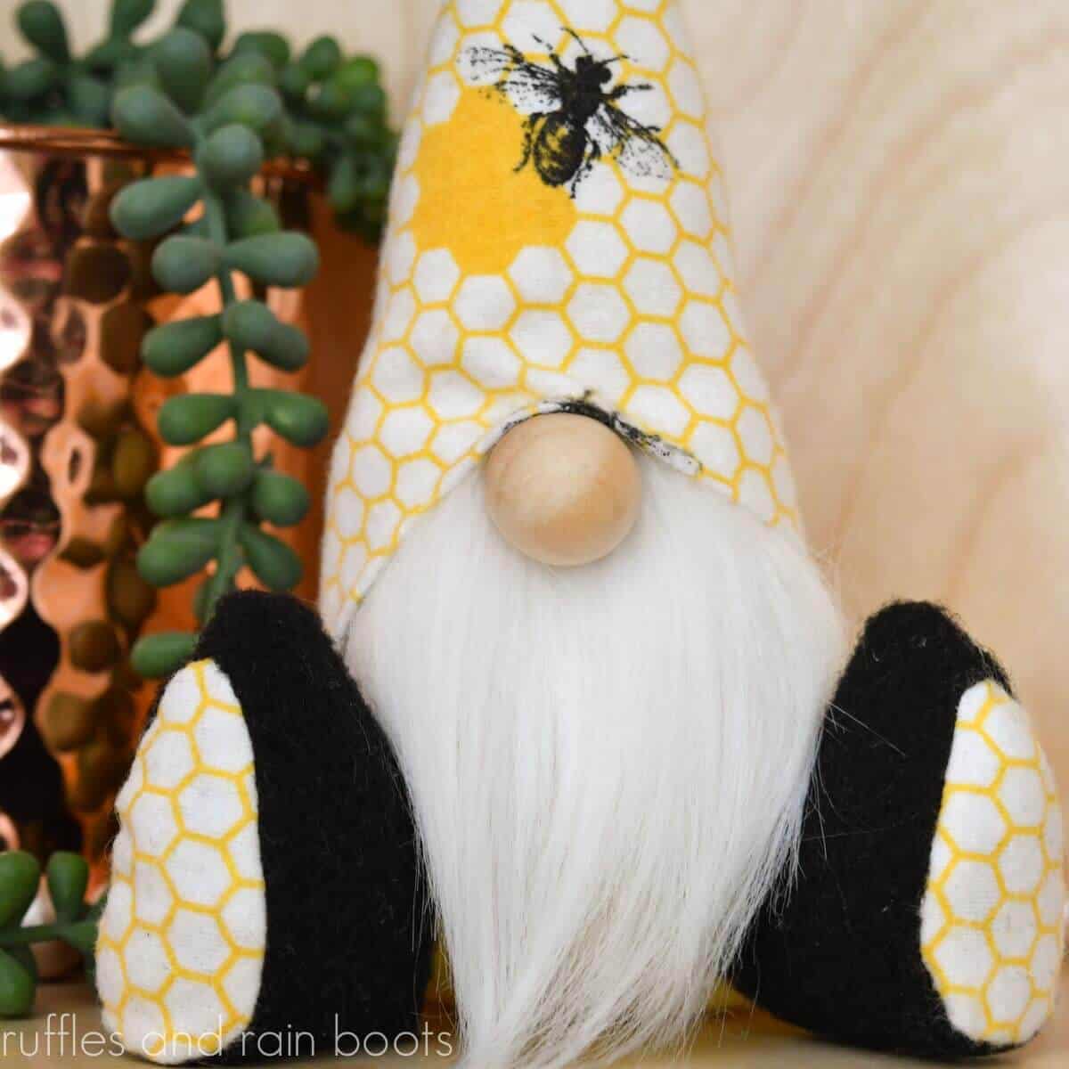 Close up of Spring mini gnome with legs made with bee fabric sitting next to a copper jar with a trailing succulent.