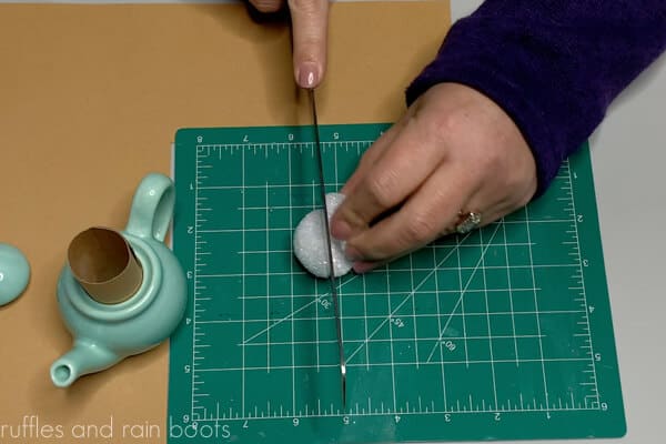 Crafter splitting a 2 inch Styrofoam ball from the Dollar Tree in half to use as gnome head.