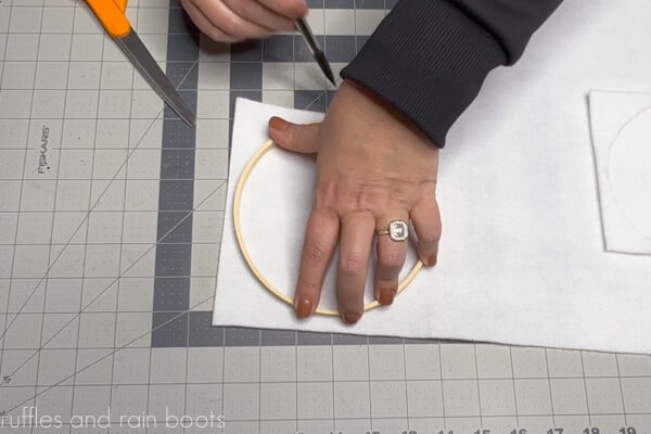 Crafter tracing the inside ring of an embroidery hoop onto felt with pencil.