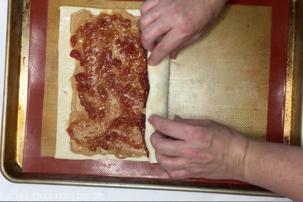 Horizontal image showing a baker rolling the peanut butter and jelly filled puff pastry on a Silpat mat.