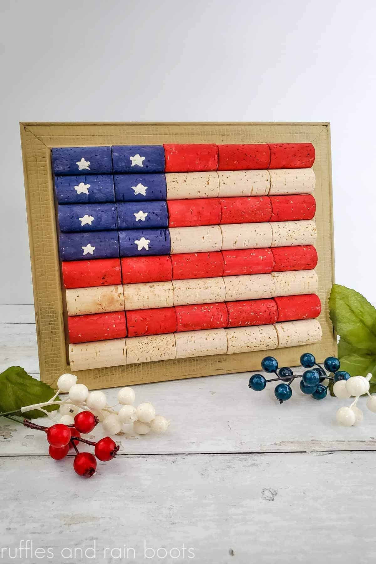Vertical image of a US flag made with corks on white wood table with red, white, and blue berry sprigs.