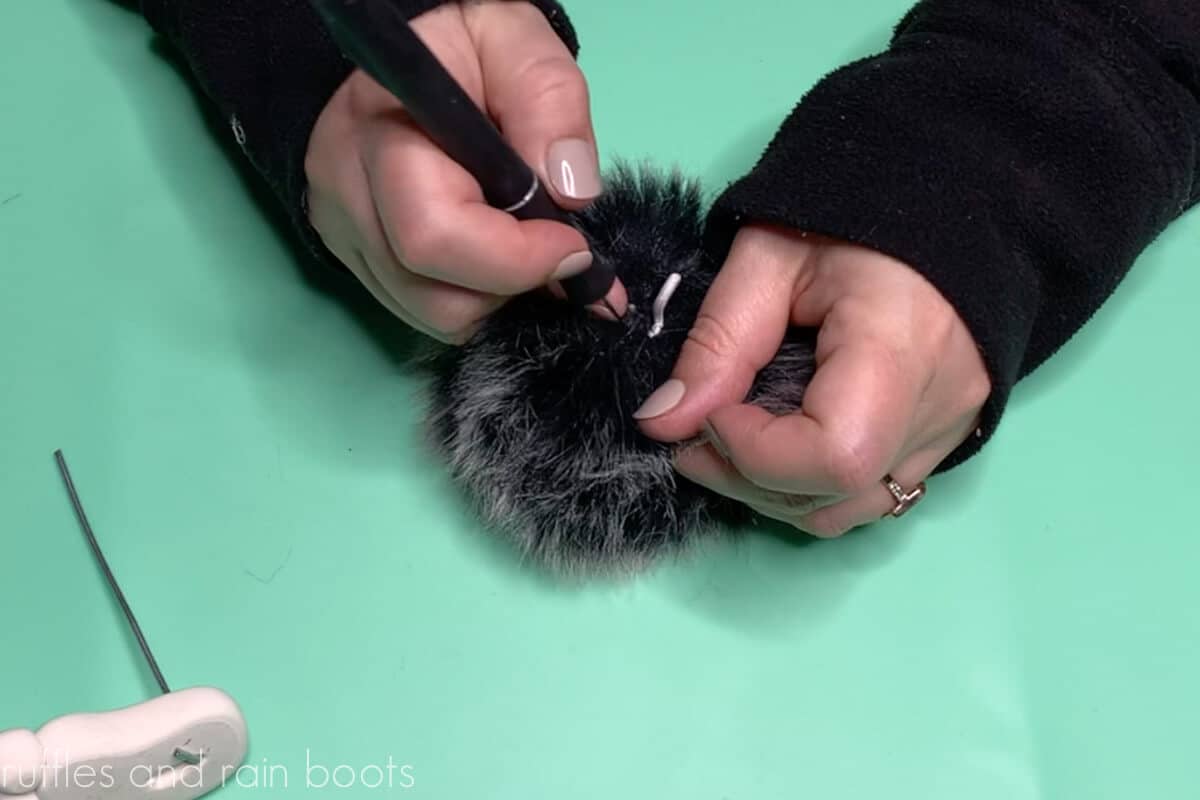 Crafter cutting open the pre-made faux fur pompom to be used for a gnome body.
