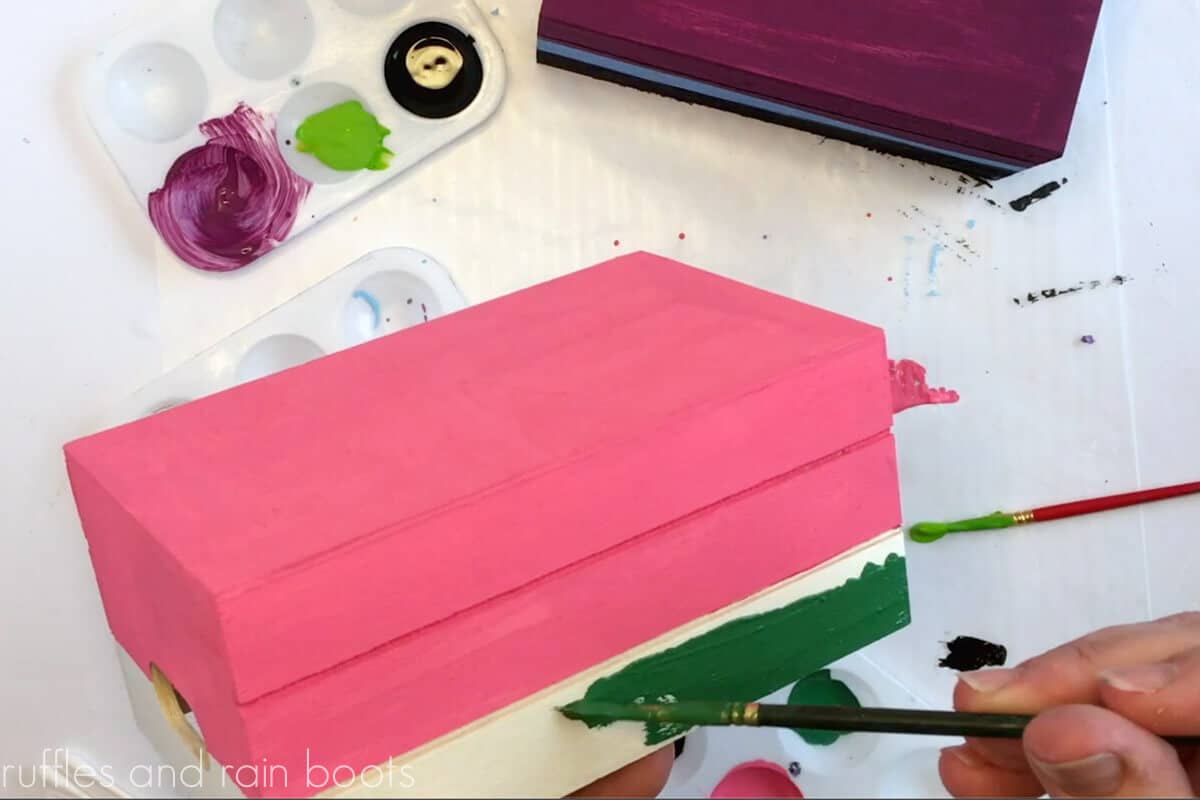 Crafter painting the bottom of the book stack a dark green for the watermelon theme.