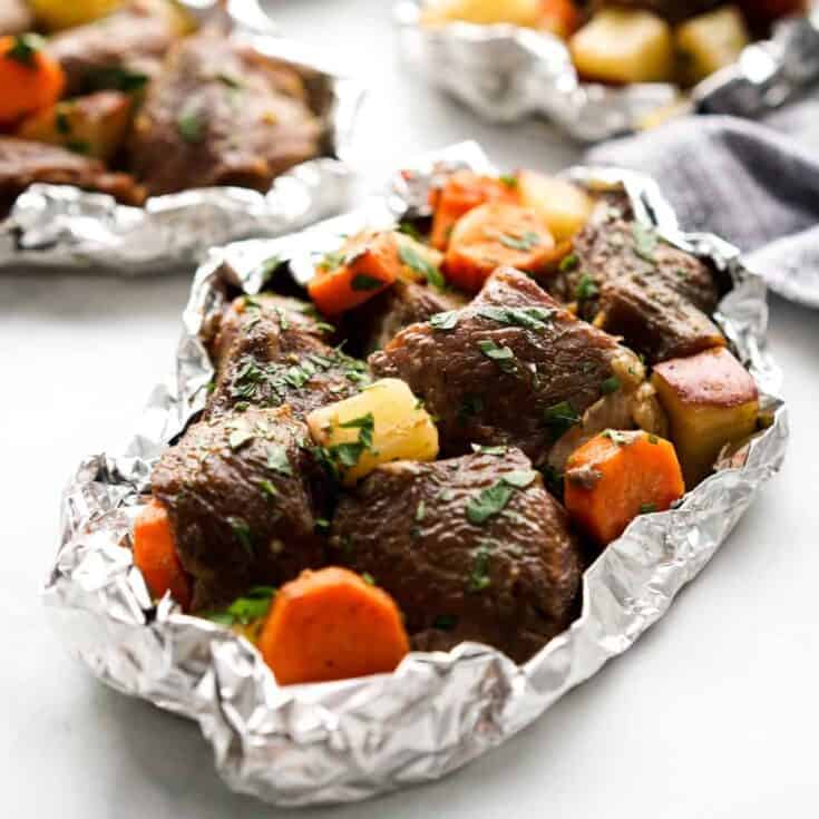 Cajun steak foil pack meal for camping on white background with carrots and potatoes.