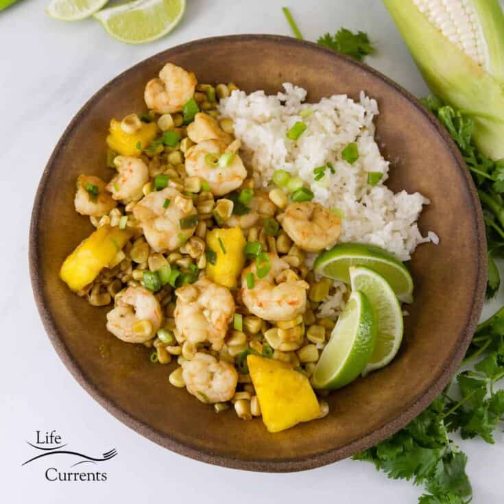 Caribbean shrimp foil pack meal for campfire cooking on a wood plate with rice and lime.
