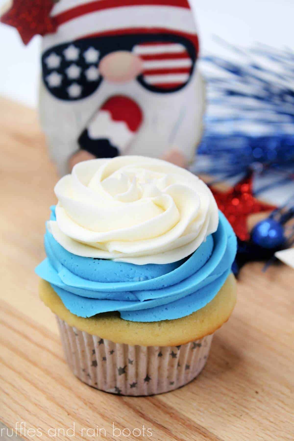 Vertical image of a two layer cupcake made with a stiff white and blue buttercream frosting recipe.