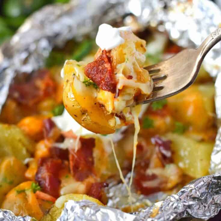 Bacon ranch foil wrapped potatoes campfire meal idea on the end of a fork.