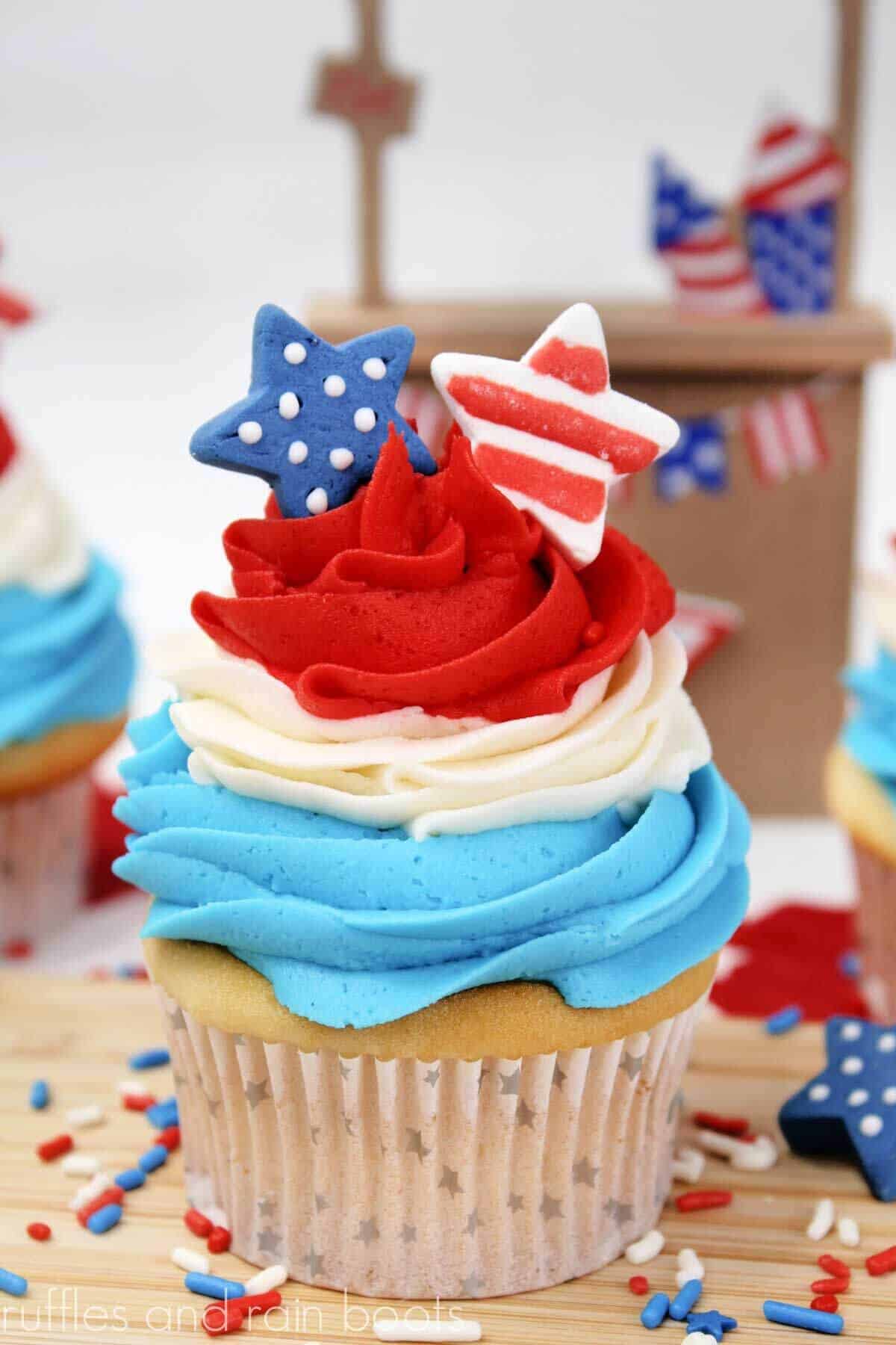 Vertical image of a red white and blue cupcake with layered frosting and star cupcake decorations.