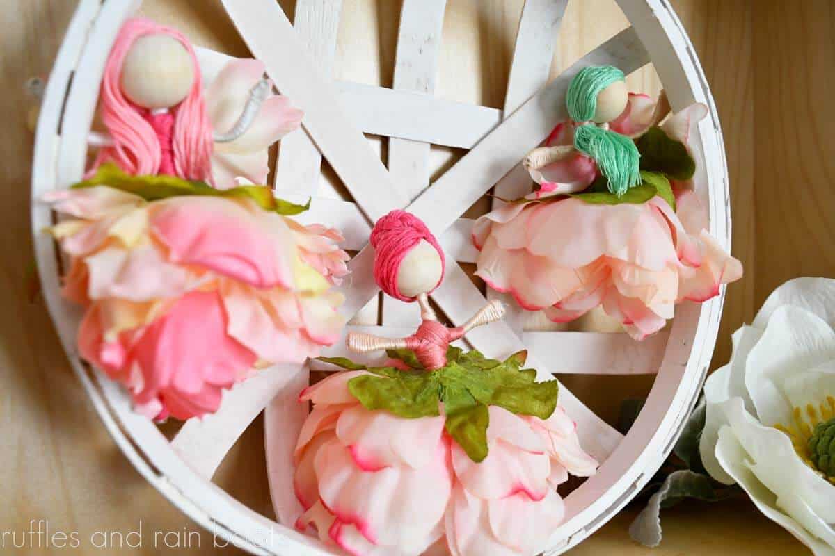 Horizontal image of three flower fairy dolls with embroidery floss hair and silk flower skirts.