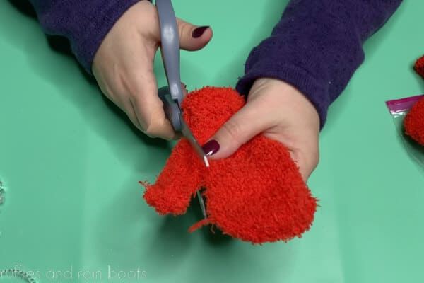 Crafter using scissors to remove the thumb from a mitten.