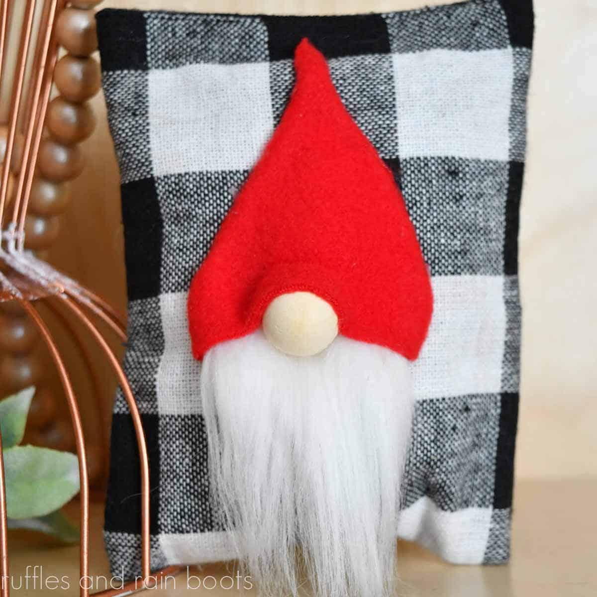 Square image of a close up red hat gnome pillow made for Christmas tiered tray decor.