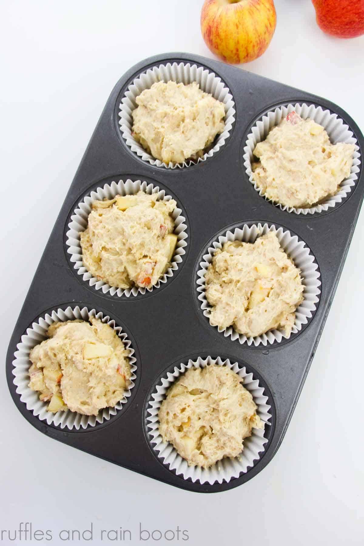 Image with apples and muffin batter in baking cups in a jumbo muffin tin.
