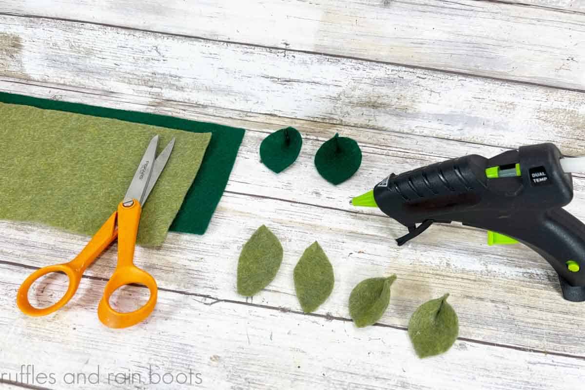 Crafter showing to cut fall leaves from green felt with small scissors and glue bottoms together.