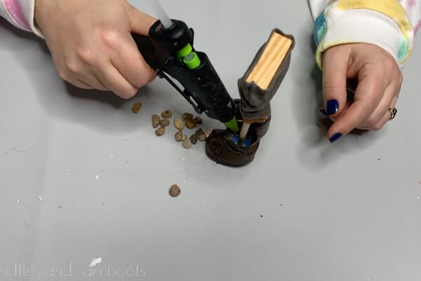Crafter using a small glue gun and small rocks to add weight to gnome boots for stability.
