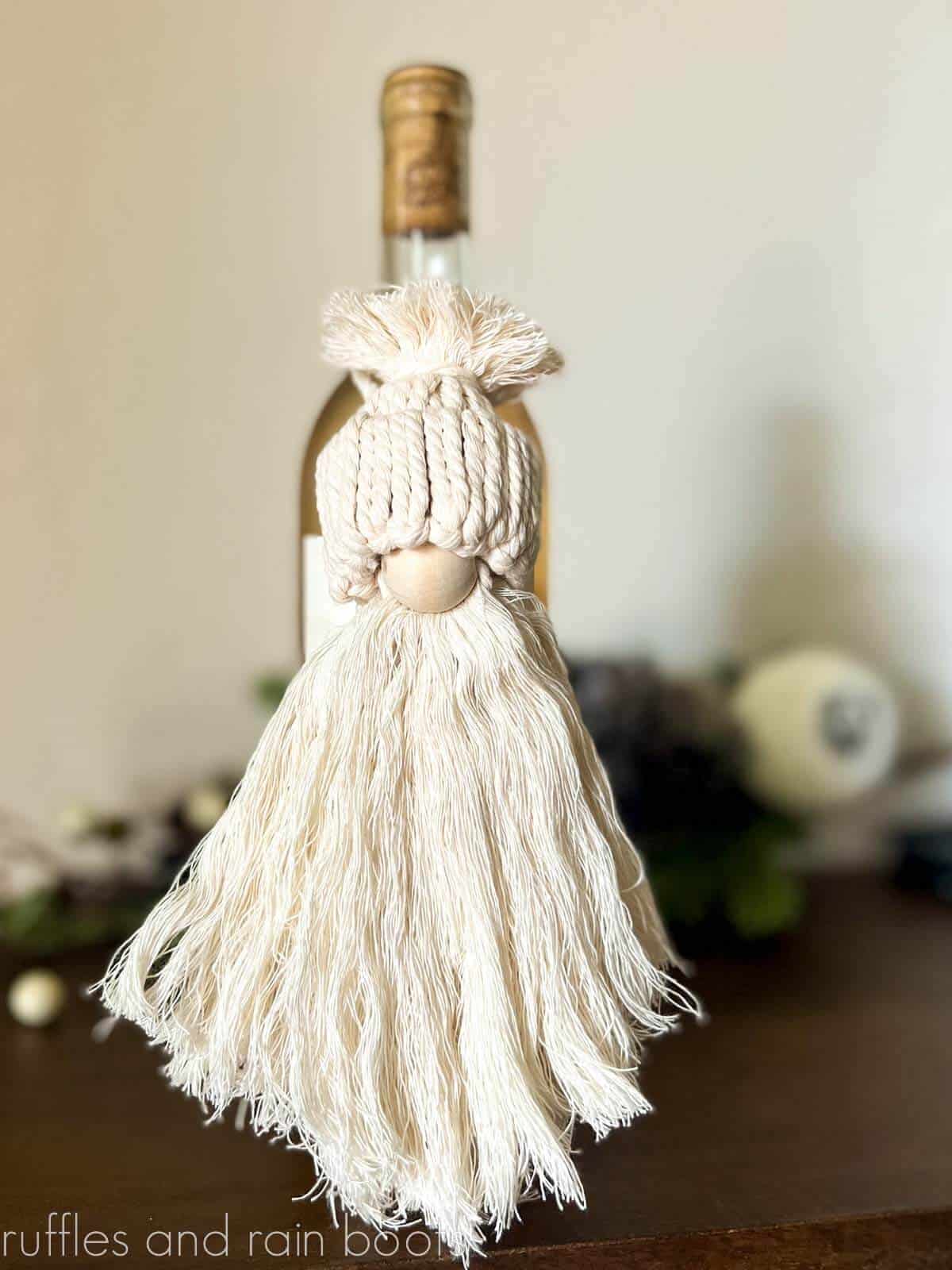 Vertical image of a neutral, natural gnome ornament made with a free macrame pattern.