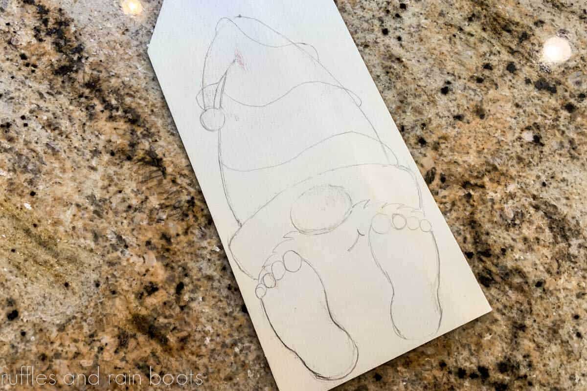 Simple drawing of a gnome on a wood tag on a granite counter.
