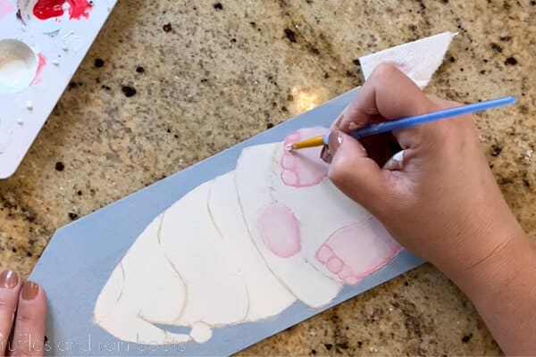 Crafter adding highlights to gnome toes on a Christmas painting.