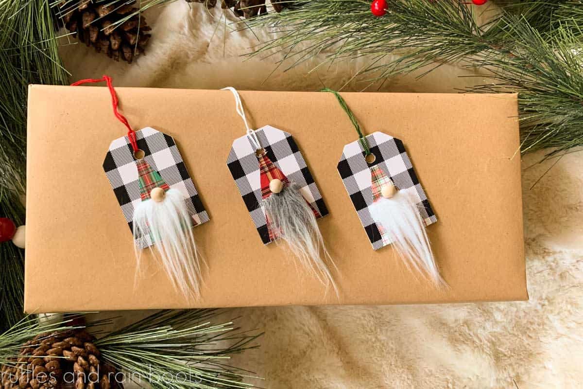Horizontal image of three wood gnome gift tags made with Dollar Tree Buffalo check vinyl, fur scraps, and wood beads.