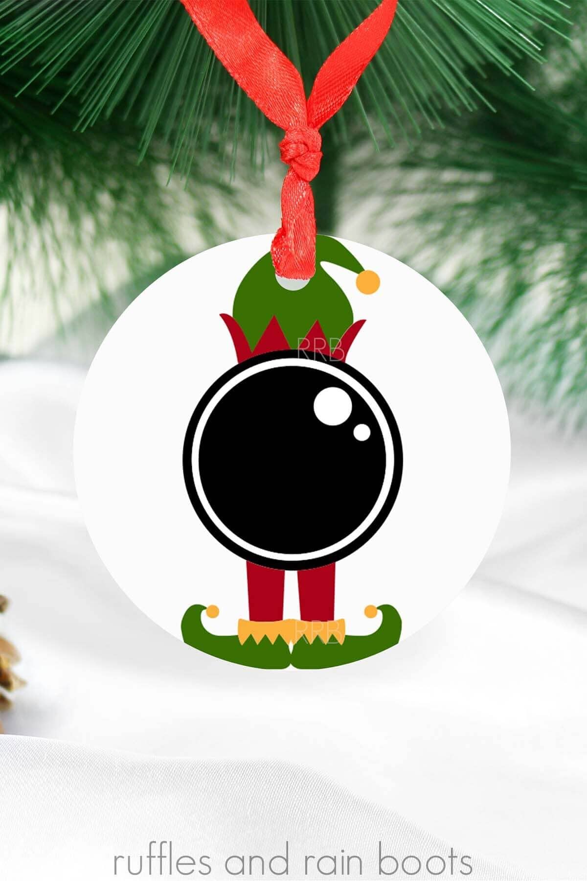 Elf cam SVG in black, red, green, and yellow vinyl on white ornament on holiday background.