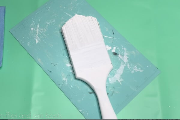 Fully painted white paintbrush from the Dollar Tree on a silicone mat.