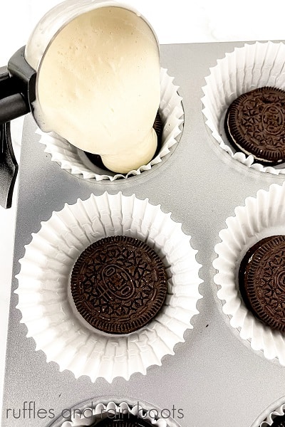 V Overhead image of the batter beikng scooped by an ice cream scroop into the prepared muffin tin for the Hedwig Cookies and Cream Cupcakes on a marble surface.