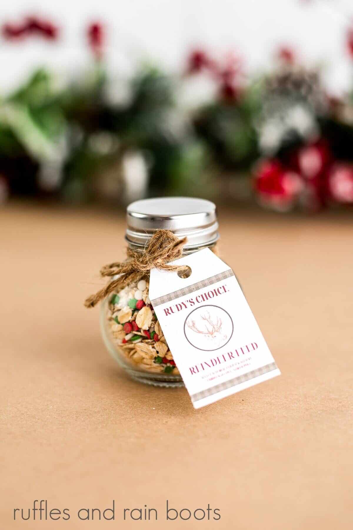 V image of Homemade Reindeer Food in a jar with free printable on a tan surface.