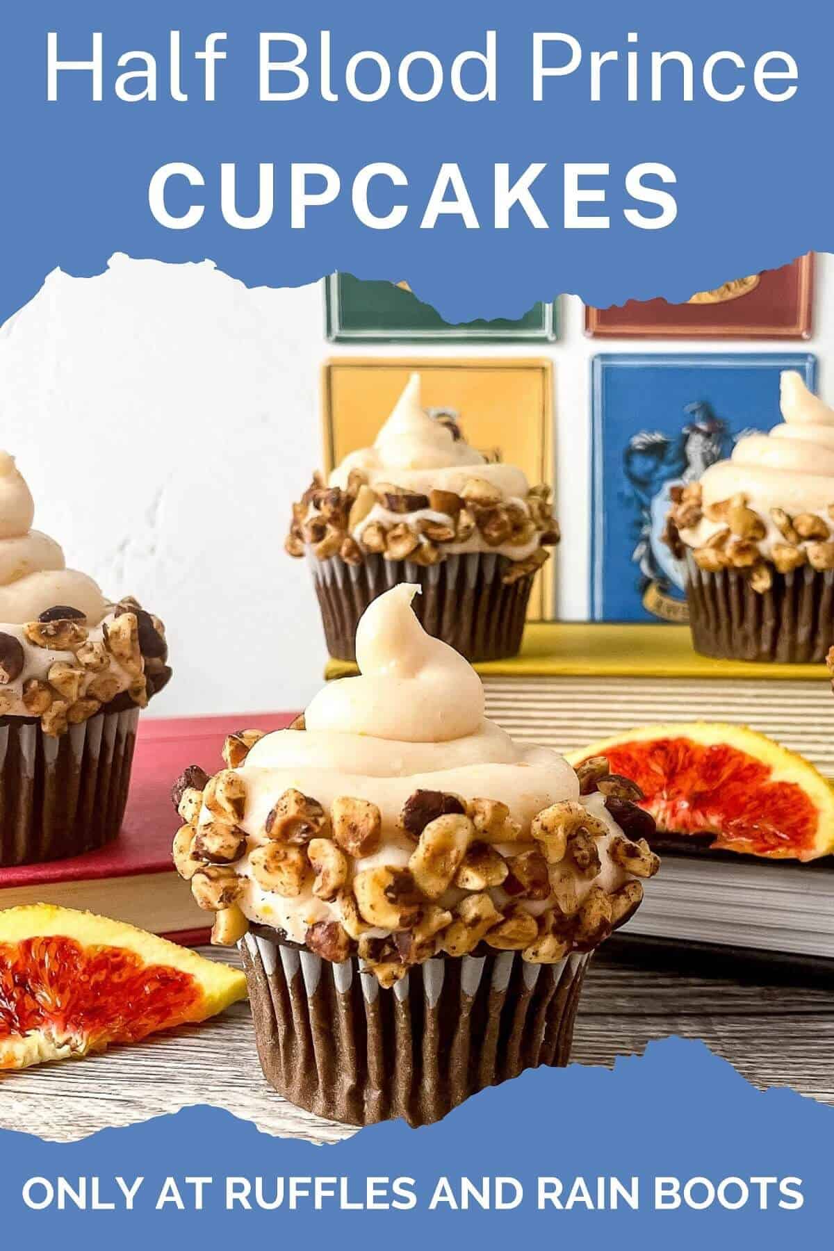 Vertical close up of a frosted cupcake with hazelnuts, next to 2 slices of a blood orange with 3 cupcakes in the background next to books and the Hogwarts house emblems on a weathered wood surface.