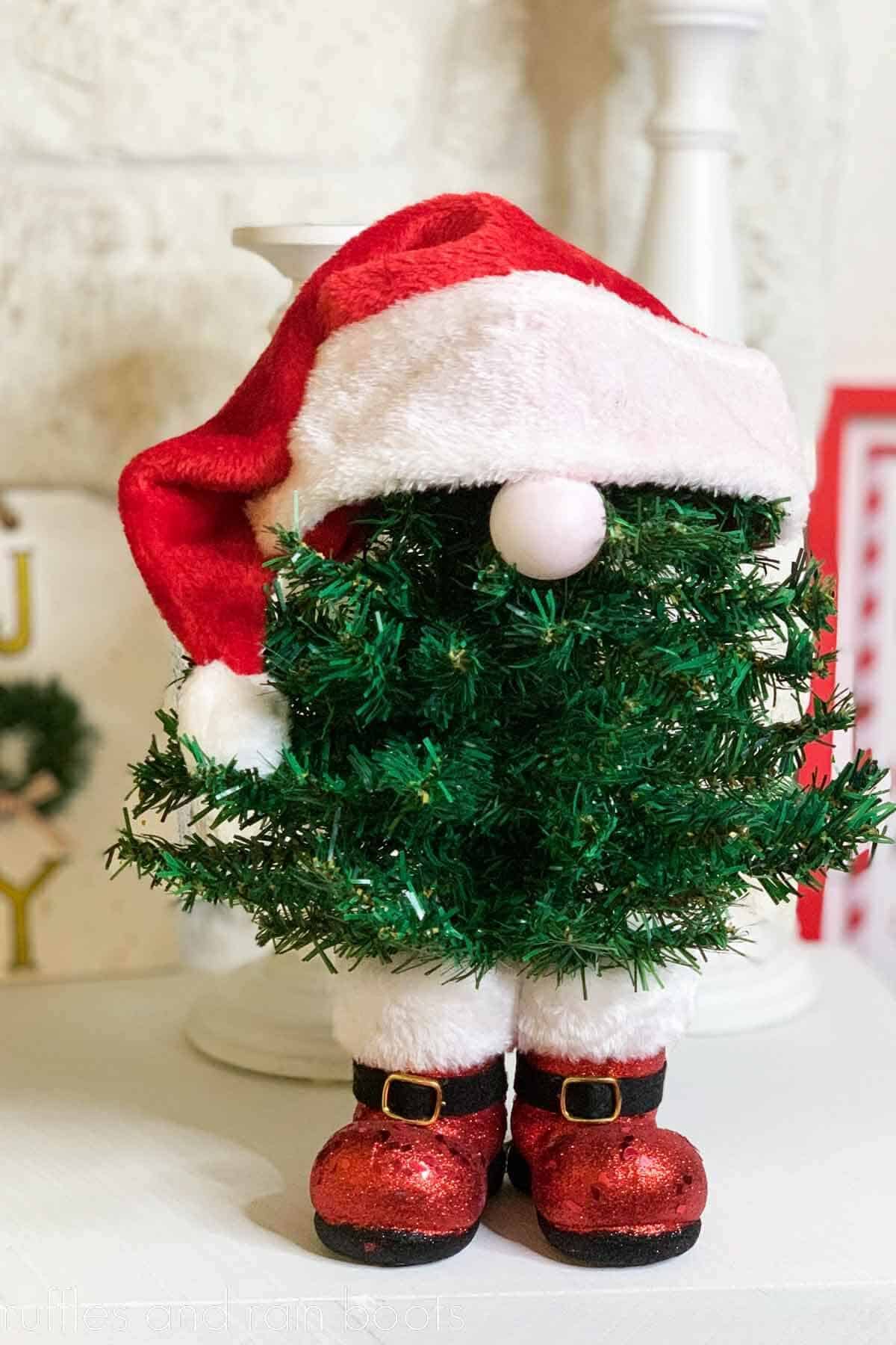 Vertical bright image of a standing Christmas tree gnome in boots made with Christmas trees from the Dollar Tree.
