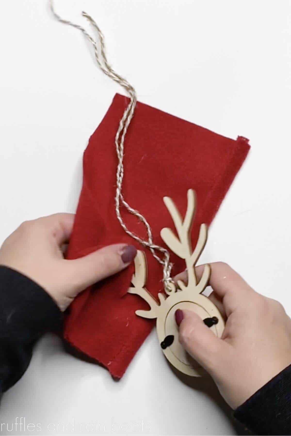 Crafter placing a gnome hat through antlers a reindeer ornament made of wood.