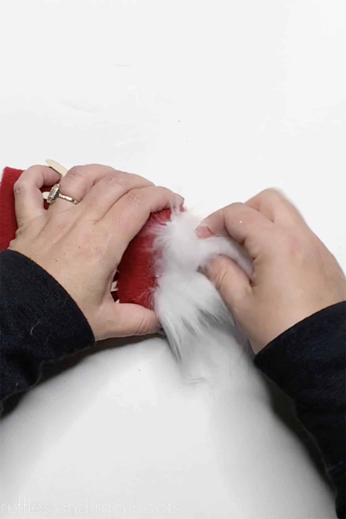 Crafters hands gluing faux fur on a gnome ornament on white background.