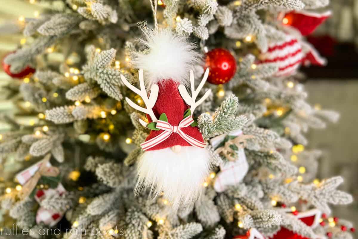 Horizontal image of a reindeer ornament with red hat on a flocked Christmas tree with red and white ornaments.