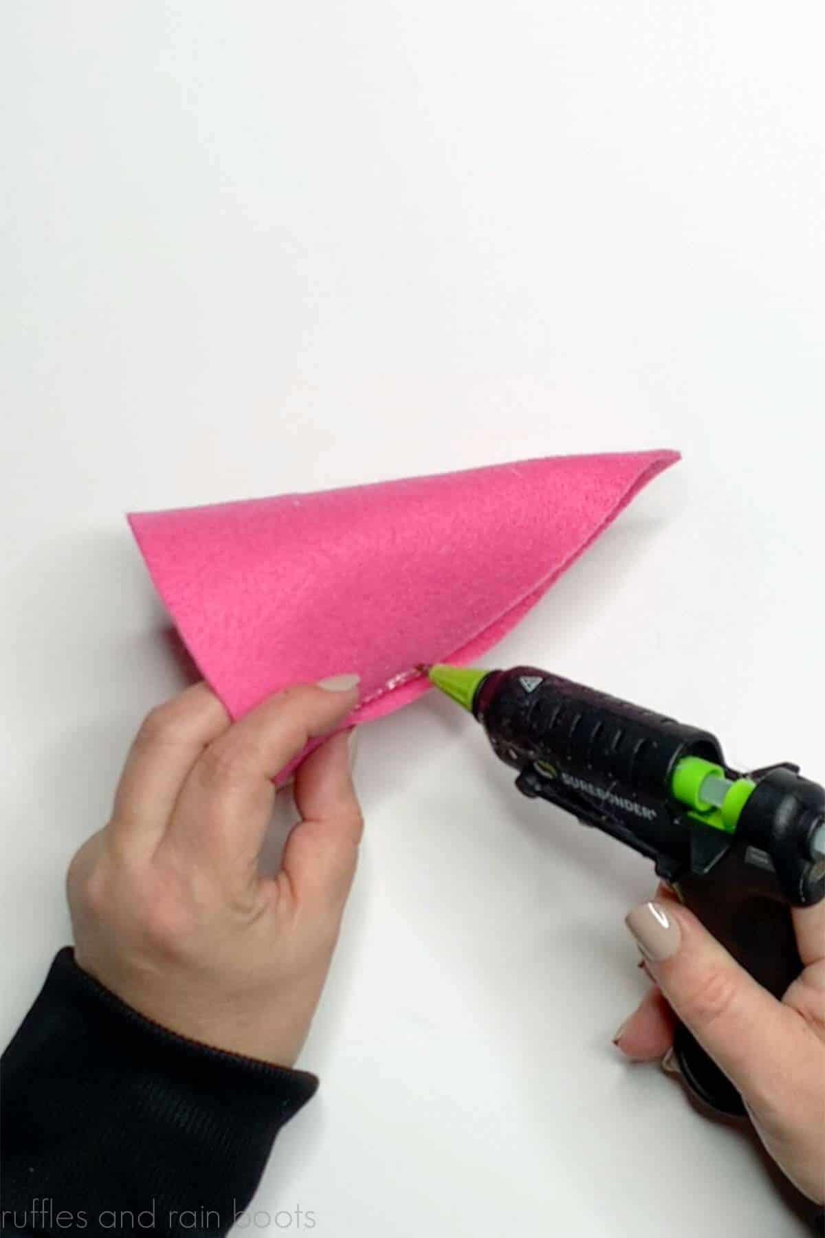 Crafter using a detail tip hot glue gun to create a pink gnome hat.