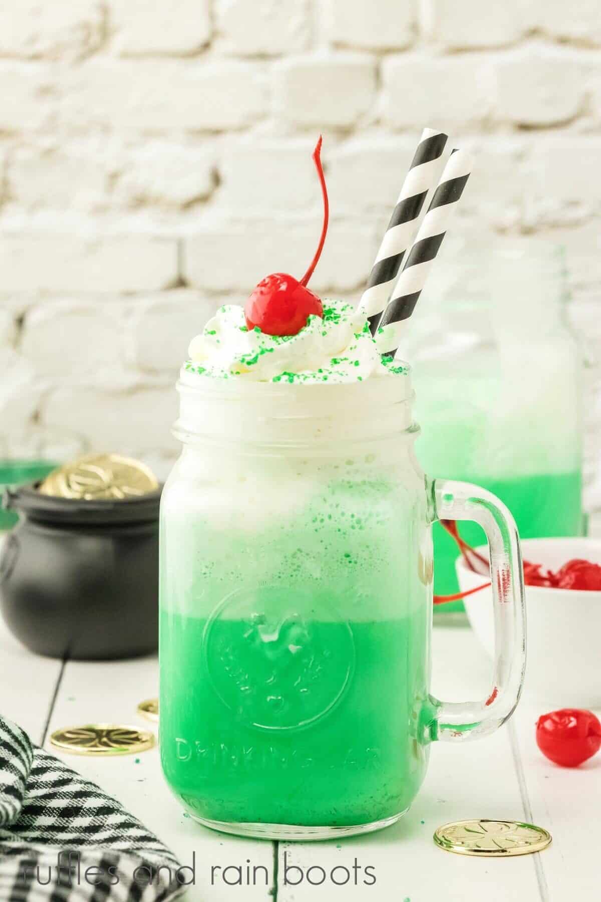 Copycat Shamrock Shake in a mason jar glass with a black pot of faux gold and a black and white napkin in the background on a white weathered wood surface.