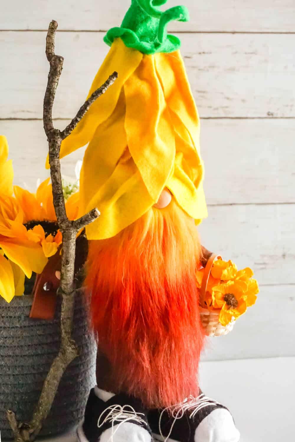 Vertical image of sunflower gnome with maroon, orange, and yellow ombre gnome beard made with cold dye.