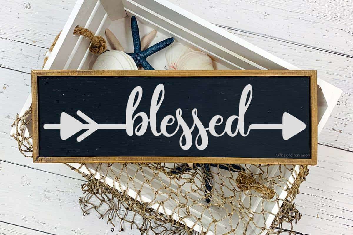 Horizontal image of a blessed navy and wood sign on top of a white crate filled with nautical decor.