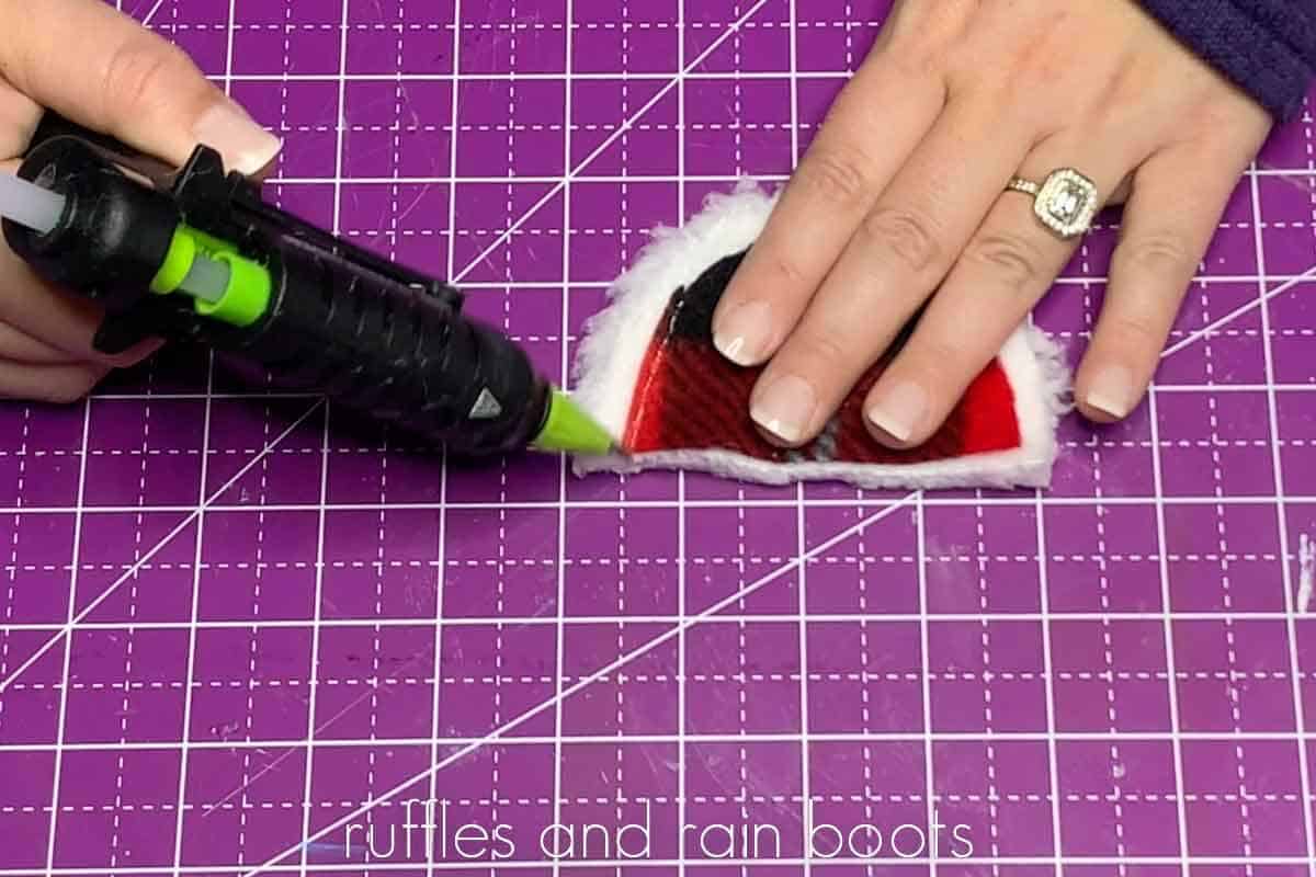 Crafter gluing an ear flap to a sherpa fleece backing for a mudflap gnome hat.