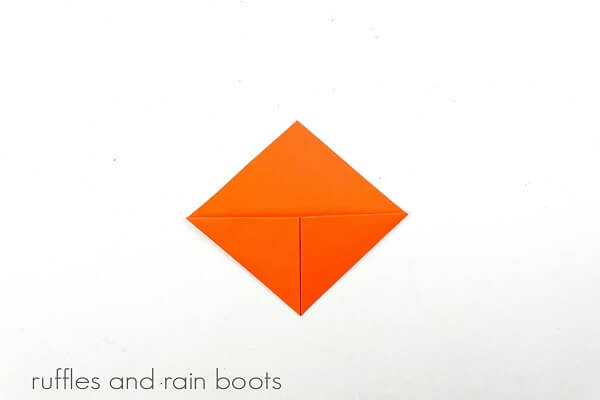 An orange folded paper bookmark on a white surface.