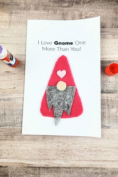 Easy Gnome Valentine's Day Card on a weathered wood surface next to a glue stick.